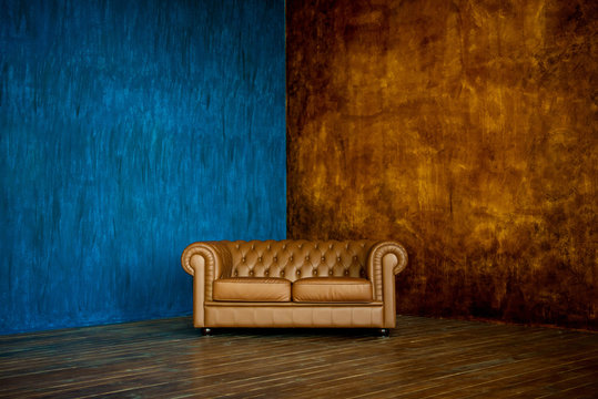 brown sofa chester on a background of blue and brown walls.