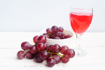 Grape and glass of wine on a white wooden floor