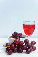 Grape and glass of wine on a white wooden floor