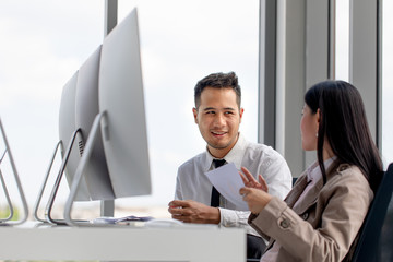 Young Asian businessmen are working together in modern office. There are many modern computers placed on the table.