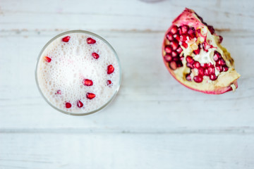 Traditional indian lassi - cold yougurt drink on white table with pomegranate seeds