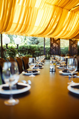 Sparkling glassware stands on long table prepared for wedding dinner