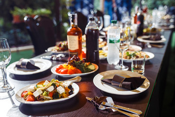 Sparkling glassware stands on long table prepared for wedding dinner.