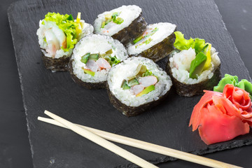 Japanese restaurant, sushi roll on black slate plate.