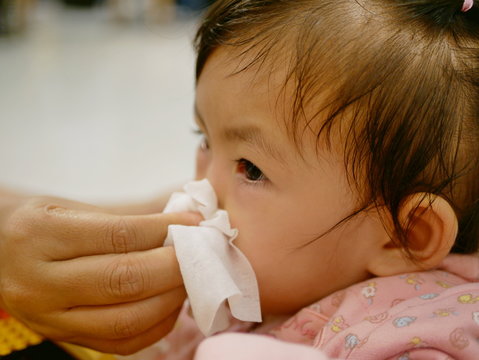 Close up of a mother hand squeezing her daughter running nose - cleanning a baby's stuffy nose