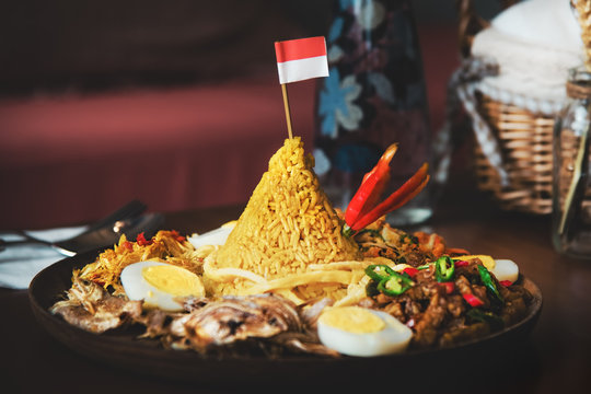 Traditional Indonesian Cuisine Nasi Tumpeng for Independence Celebration with Flag. Tumpeng is a cone-shaped rice dish like mountain with meats