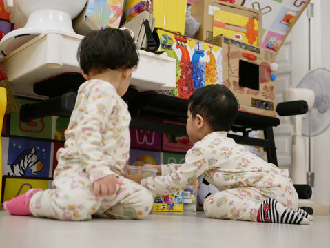 Asian Baby, 31 Months Old, (right) Is Cleaning Up / Putting Away Toys She Played With Her Little Sister