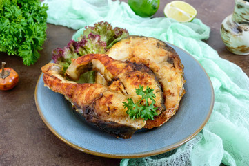 Large steaks of grilled fish with lettuce on a plate.