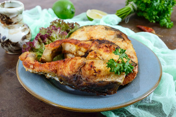 Large steaks of grilled fish with lettuce on a plate.