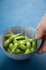Frau isst Portion grüne, japanische Edamame Sojabohnen in Porzellan Schale