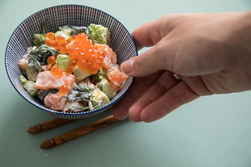 Frau serviert rohes Lachs Avocado Tatar mit Keta Kaviar und Holz Stäbchen