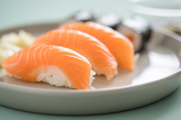 Japanese salmon Nigiri and Maki Sushi with pickled ginger and wooden chopsticks on porcelain plate
