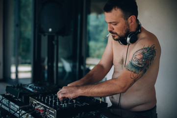 DJ smoke cigarette and plays music on player and mixer