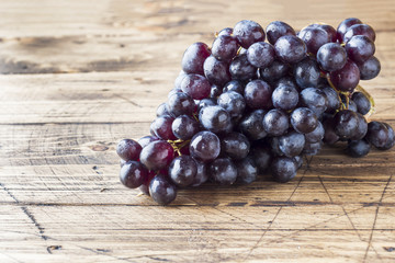 bunch of fresh black grapes on a wooden wooden table are a selective focus.