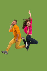 Full length of young couple with mobile phone while jumping