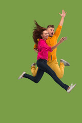 Full length of young couple with mobile phone while jumping