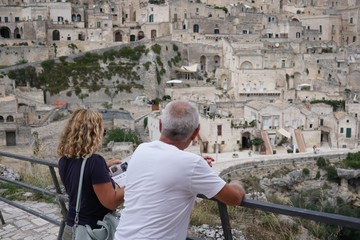 Unrecognizable back turned people looking at the famous Sassi di Matera, two districts of the Italian city of Matera, Basilicata, well-known for their ancient cave dwellings