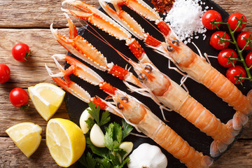 beautiful set of fresh raw langoustine, scampi with seasonal vegetables and herbs closeup on a...