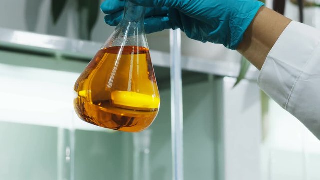 oil products of different colors and hand shows yellow liquid