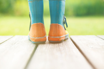 rubber boots on a wooden background. children's rubber boots on a background of green grass