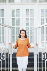 Smiling mature woman opening gate of her house