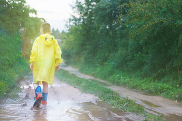 child in rubber boots playing in a puddle