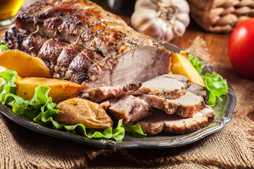 Roasted pork loin with baked potatoes and herbs