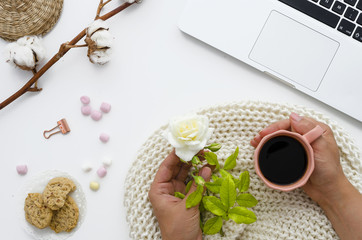 a woman holds her morning coffee and a beautiful white rose in her hands. A good start to the day Cotton flowers decorate the table. Autumn or Winter concept. Flat lay, top view