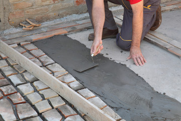 Old tiles recycling, making terrace or pavement using tile pieces,  workers hand spreading mortar or tile adhesive using trowel