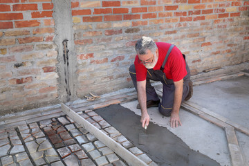 Old tiles recycling, making terrace or pavement using tile pieces,  worker spreading mortar or tile adhesive using trowel