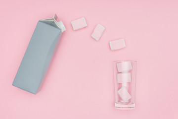 top view of marshmallows, glass and carton package isolated on pink