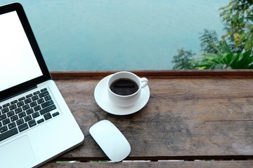 Mockup image of laptop with blank white screen on wooden table in terrace nearby river.