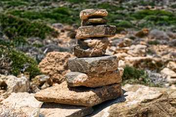 Pyramid of stones in nature. Rocks and plants in the background.