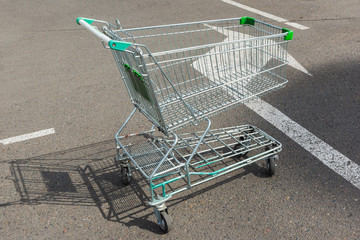 empty shopping cart  on a asphalt pavement..green plastic parts on cart