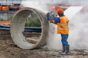 Worker at the construction site cuts the ring for the well with concrete cutters