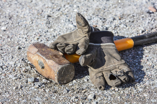 Broken work gloves and big hammer on the ground in Finland.