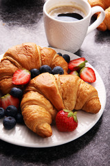 Delicious breakfast with fresh croissants and ripe berries on old marble background