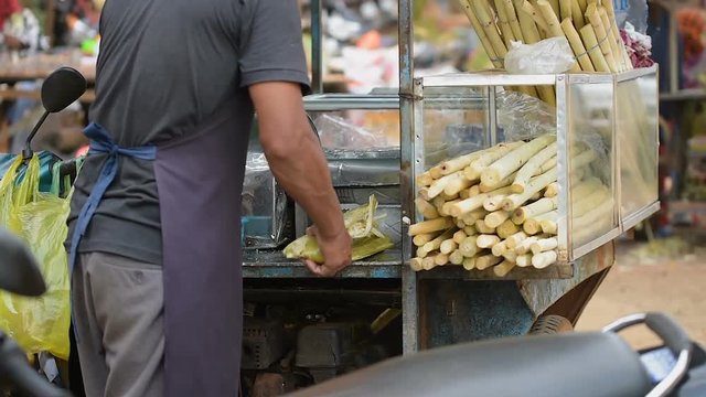Cambodian man extracting sugar cane juice using machine on the street. In Cambodia, this super sweet juiceis is very popular. Sometimes they mix this juice with lemon to make better taste.  