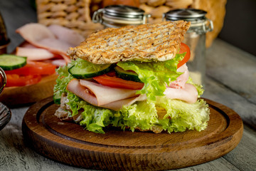 Sandwich with ham, cucumber, tomato and lettuce.