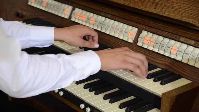 Man playing a church organ on Christmas Midnight Eve. Man's hands playing organ music in church for wedding. Musician hands on keyboard. 