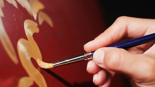 artist draws Khokhloma patterns with gold oil paint on fridge