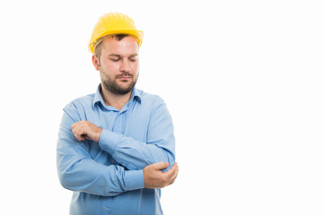Young architect with yellow helmet showing elbow pain gesture