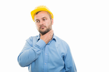 Young architect with yellow helmet showing throat pain gesture