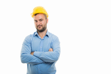 Young architect with yellow helmet standing with arms crossed