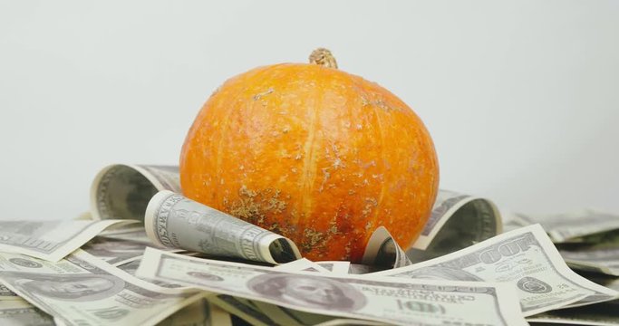 Pumpkin lying on pack of hundred dollar banknotes