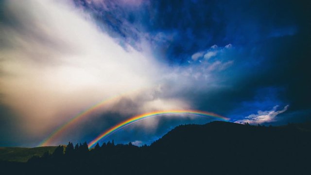Cinemagraph time lapse of rainbow over mountains after storm
