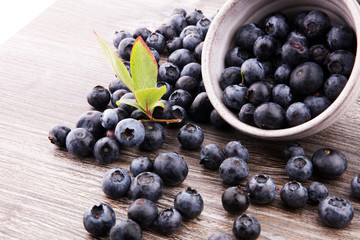 Freshly picked blueberries in wooden bowl. Juicy and fresh blueberries with green leaves on rustic table. Bilberry on wooden Background. Blueberry antioxidant. Concept for healthy eating and nutrition