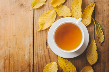 Autumn tea on wooden table with leaves