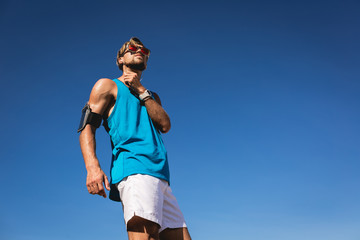 bottom view of sportsman in sunglasses with smartphone armband