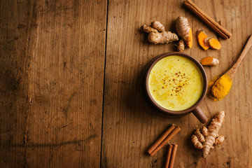 Hot turmeric milk with spices on wooden table